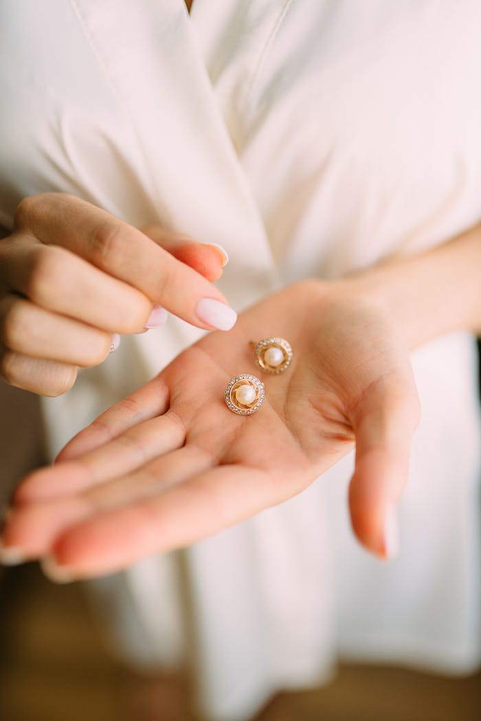 Home Close-up of elegant pearl earrings held in a hand, showcasing luxury jewelry.