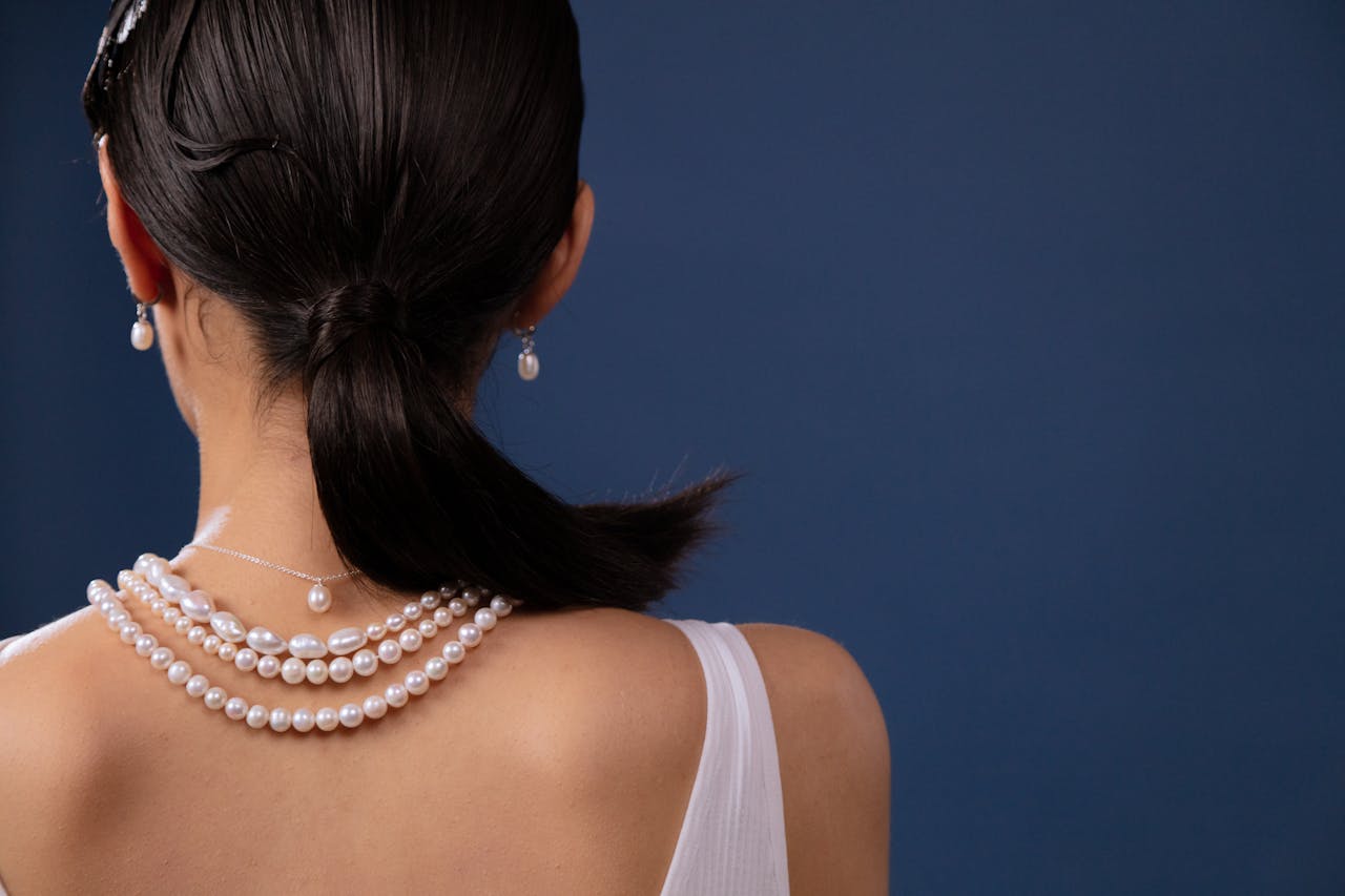 Home Close-up of a woman wearing pearl jewelry, showcasing elegance and style.